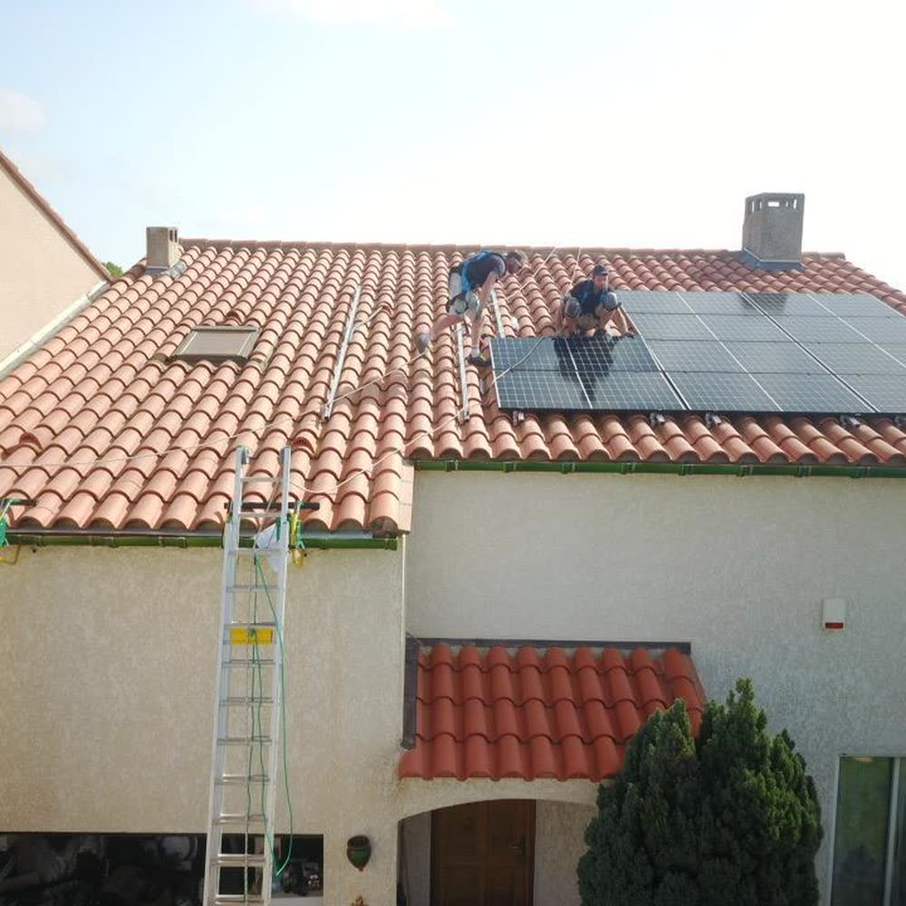Maison en cours d'équipement photovoltaïque par Elec Froid, échelles en façade et techniciens sur le toit